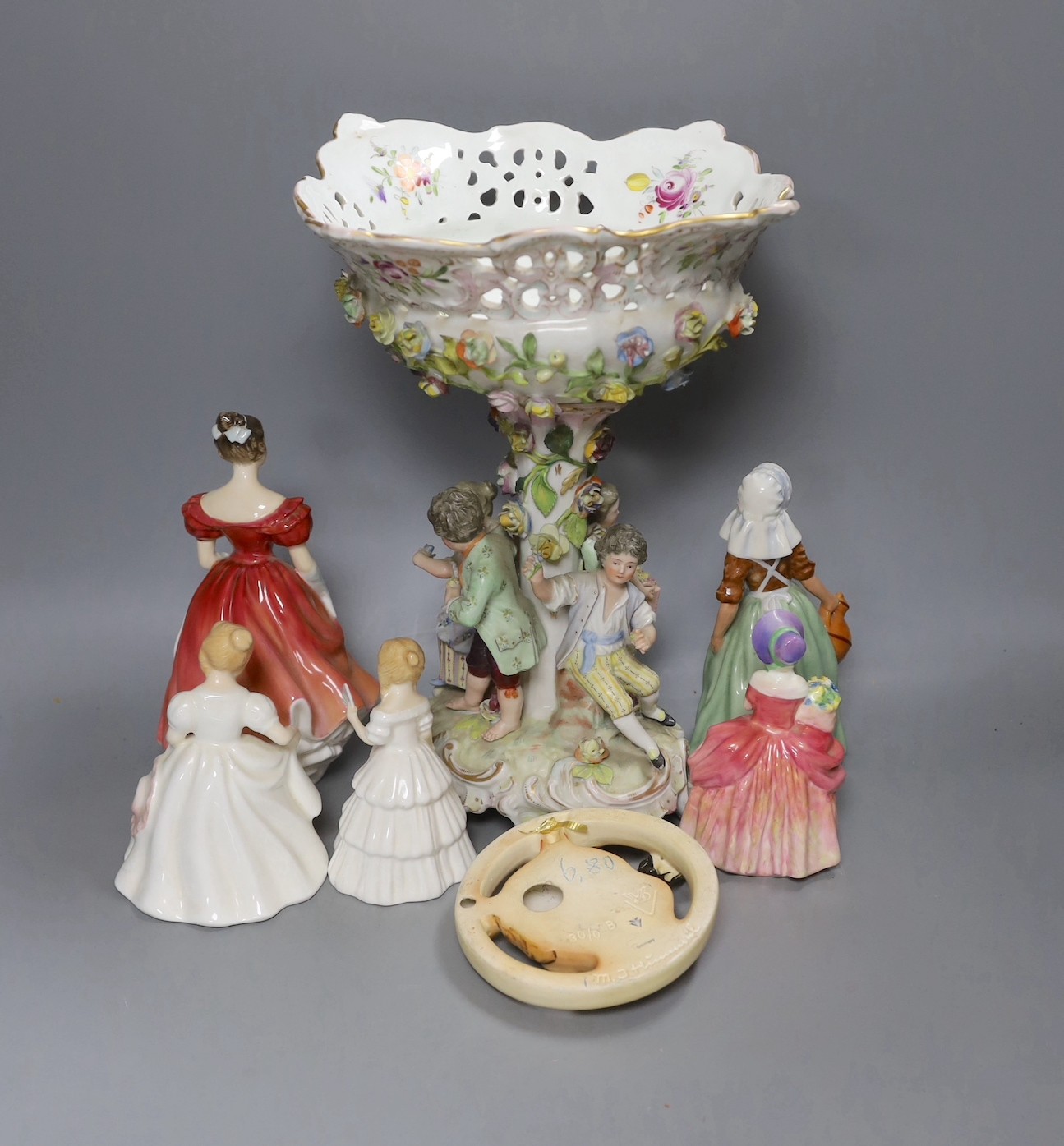 Five Royal Doulton figurines, a Hummel hanging and a Sitzendorf style table centre, 33cm tall